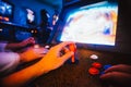 POV angle on hands playing vintage arcade game with an opponent, in a dark shade room full of arcade games