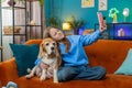 POV of excited girl child kid with cute beagle dog pet taking selfie on smartphone at home room