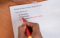 POV close up shot of hands checking Covid-19 vaccine report card and ticking 3rd or booster dose after vaccination