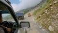 POV: Driving along bumpy road past small excavator fixing damage after landslide Royalty Free Stock Photo