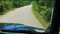 POV driving jeep on winging rough path between green plants