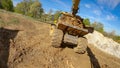 POV: Excavator arm scoops up a bucket full of soil and dumps it on the trailer. Royalty Free Stock Photo