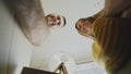 POV of happy couple kissing while opening cardboard box after relocation and looking inside and taking things in new Royalty Free Stock Photo