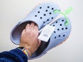 POV male hand holding pair of new Crocs sandals foam clogs in bl