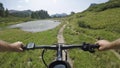POV man riding e-bike on hill near lake.Mtb action cyclist exploring trail path near mountains.Electrical bike active