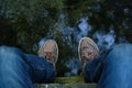 POV men feet in sneakers hanging from bridge over river. Top view male legs dangling over water. Guy enjoying time alone sitting