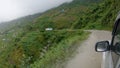 POV: Shot of driving along a bumpy dirt road on the edge of a steep grassy hill.