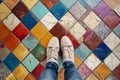 Pov shot looking down on a persons feet standing on a brightly colored geometric mosaic tiled floor