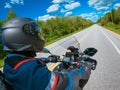 POV side view biker riding motorcycle against blue sky, green trees along the asphalt road. First-person view. Focus on the