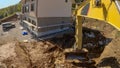 POV: Using a Caterpillar excavator to excavate soil near an unfinished house.