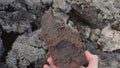 POV view male hand taking big piece of rock covered with moss and curiously examining it. Geology studies outdoors