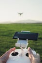 POV view - Man control the drone by remote control over the meadow on sunset. Man operating the drone and flying over the field Royalty Free Stock Photo