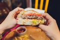 POV woman eating hamburger hand holding half eaten hamburger