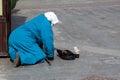 Poverty. Elderly old woman begging for alms from people, kneeling on the street