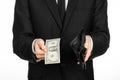 Poverty and money theme: a man in a black suit holding a empty wallet and banknote 1 dollar on white isolated background in studio Royalty Free Stock Photo