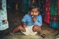 Poverty, a picture of a little poor Indian girl in old ragged clothes sitting on the floor. Chocolate baby