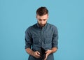 Poverty and unemployment. Desperate young man showing empty wallet with no money over blue studio background Royalty Free Stock Photo