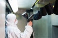 Powder coating of metal parts. A man in a protective suit sprays powder paint from a gun on metal products Royalty Free Stock Photo