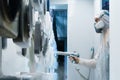 Powder coating of metal parts. Man in a protective suit sprays white powder paint from a gun on metal products Royalty Free Stock Photo