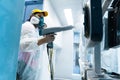 Powder coating of metal parts. A woman in a protective suit sprays white powder paint from a gun on metal products Royalty Free Stock Photo