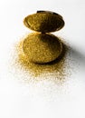 Powder highlighter in a gold powder box with gold sparkles reflected in the mirror. Isolated on white background.