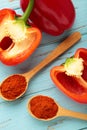 Powder paprika on wooden spoon with fresh red pepper on blue wooden background. Vertical photo Royalty Free Stock Photo