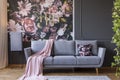 Powder pink blanket thrown on grey couch in real photo of dark s Royalty Free Stock Photo