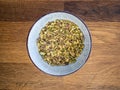 Powdered broken naked pistachio nuts in a white bowl on a wooden table