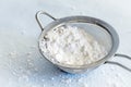 Powdered Confectioners Sugar in Sieve Closeup over Pastel Blue