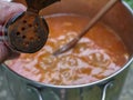 Powdered paprika can in hand with stew pot in background