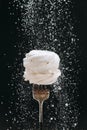 Powdered sugar falling over vanilla meringue on fork, black background Royalty Free Stock Photo