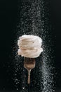 Powdered sugar falling over vanilla meringue on fork, black background Royalty Free Stock Photo