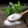 Powdered sugar in a wooden spoon, with fresh stevia leaves, on a wooden background