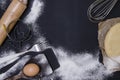 Powdering by flour rolled out dough for bakary stics with wooden rolling pin over black basground. Royalty Free Stock Photo