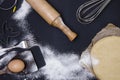 Powdering by flour rolled out dough for bakary stics with wooden rolling pin over black basground. Royalty Free Stock Photo