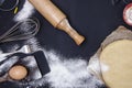 Powdering by flour rolled out dough for bakary stics with wooden rolling pin over black basground. Royalty Free Stock Photo