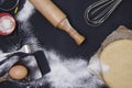 Powdering by flour rolled out dough for bakary stics with wooden rolling pin over black basground. Royalty Free Stock Photo