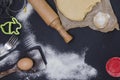 Powdering by flour rolled out dough for bakary stics with wooden rolling pin over black basground. Royalty Free Stock Photo