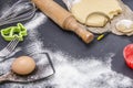 Powdering by flour rolled out dough for bakary stics with wooden rolling pin over black basground. Royalty Free Stock Photo