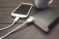 Power bank charging a smart phone next to a cup of coffee Royalty Free Stock Photo
