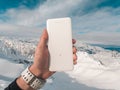 Power bank in hands. Tourist charges a devices in nature, against the backdrop of a winter mountains landscape