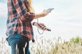 Power bank in the hands of a girl with a smartphone, against the background of a yellow field