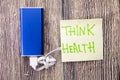 Power bank and a note with the words Think Health are present on a woody surface.a state of physical, mental and social well-being