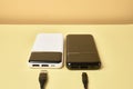 Power banks for charging mobile devices. White and black charger with cable. External battery for mobile devices.