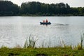 Power boat with people fishing on the pond in the countryside in summer.
