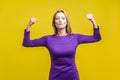 Power and female inner strength. Portrait of proud successful businesswoman demonstrating biceps. studio shot isolated on yellow