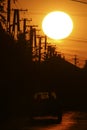 The power grid can be seen at sunset next to a road leading to the city, with a silhouette of a car and two passengers on it. Royalty Free Stock Photo