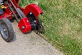 Power lawn edger trimming grass along sidewalk.