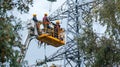 Power line maintenance workers on elevated platform repairing electricity transmission tower work job Royalty Free Stock Photo