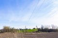 A power line over a field and against a blue sky background Royalty Free Stock Photo